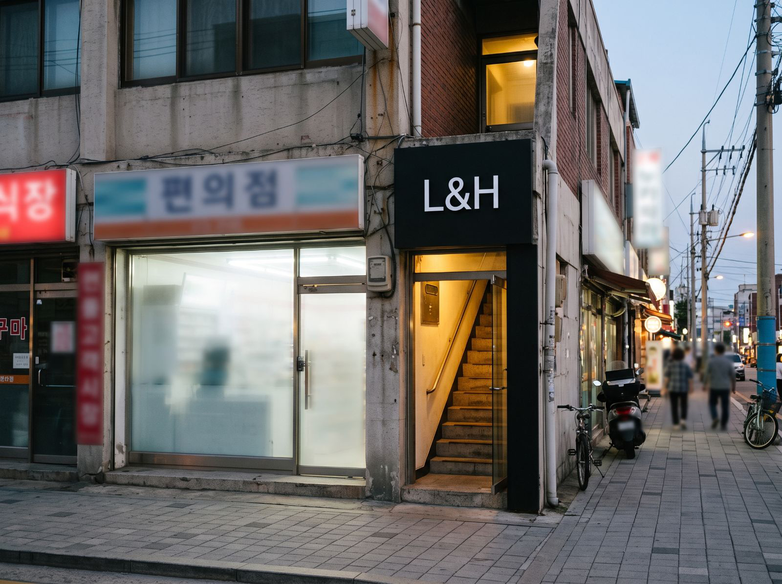 1층 편의점 옆 계단과 검은 L&H 간판이 보이는 매장 입구